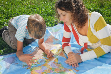 mother and son studies a political card of the world, being on the nature