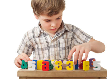 boy in checkered shirt displays wooden figures in form of numerals on table isolated on white...