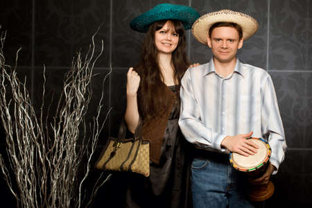 young beautiful woman and smiling man in sombrero and with drumの写真素材