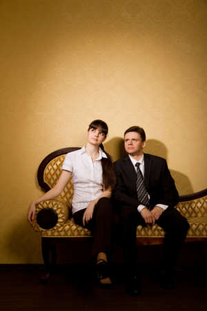 young beautiful woman and businessman in suit sitting on sofa in roomの写真素材