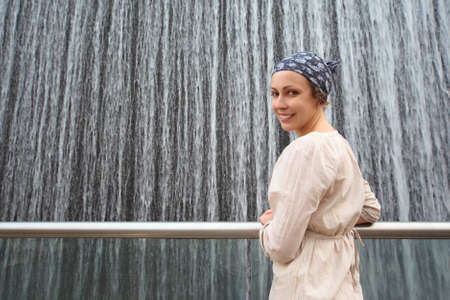 young beauty woman in white shirt standing near big fountain and looking back, half bodyの写真素材