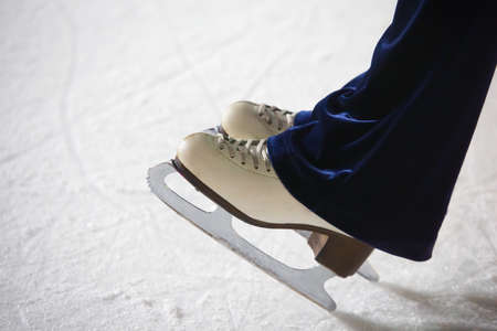Human feet in fads standing on ice on the brink of an edge on skating rinkの写真素材