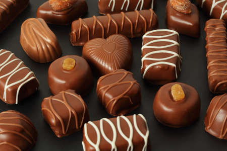 many chocolate appetizing candys with icing on dark background