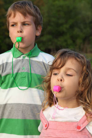 Beautiful small children, the boy and the girl, play with whistles. Focus on girl.の写真素材