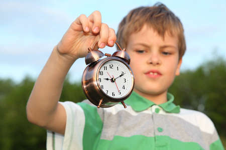The nice boy, against the nature, has control over a beautiful classical alarm clock.の写真素材