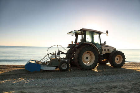 Tractor with  trailer in  morning takes garbage away on  beachのeditorial素材