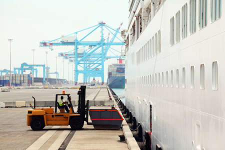 cargo loading in dock, two workers and loader near big white ship, inserted released faces