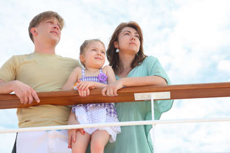 family with daughter standing on cruise liner deck near rail, child standing on fence, half bodyの写真素材