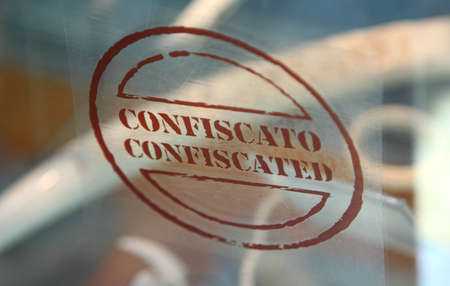 Brown inscription of two brown word confiscated and confiscato on a transparent glass, shallow depth...