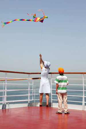 young mother and son playing with multicolored kite, standing on cruise liner deckのeditorial素材