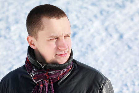 Young man stands on snow in winter and dreamily looks farの写真素材