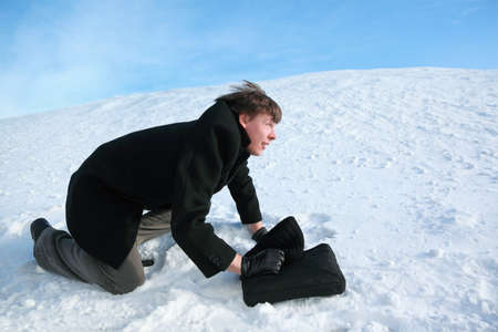 Young man creeps on all fours on snow with  brief-caseの写真素材