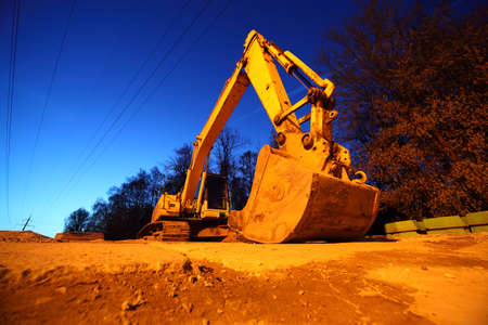 Big yellow crawler tractor with big bucket on yellow sands at nightのeditorial素材