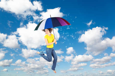 flying woman with rainbow umbrella on White, fluffy clouds in blue sky with moon collageの写真素材