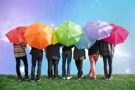 seven friends with rainbow color umbrellas on meadow collageの写真素材