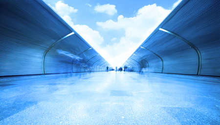 people are standing and going at subway station, sky with cloudsの写真素材