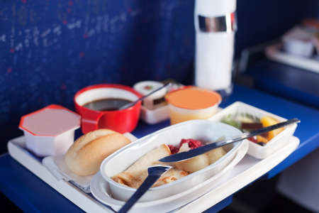 Tray of food on the plane. Focus on a plastic cruet stand with pancakes. Shallow depth of focus.