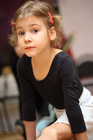 little girl in ballet class sits on string on floor and looks into cameraの写真素材