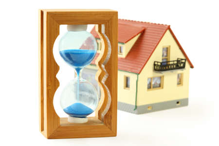 toy house with red roof and hourglass with blue sand isolated on white