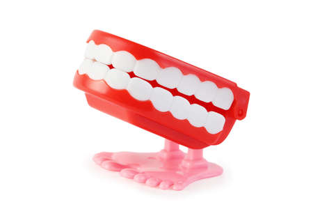 side view of bright toy clockwork jaw with white teeth on pink legs on white background
