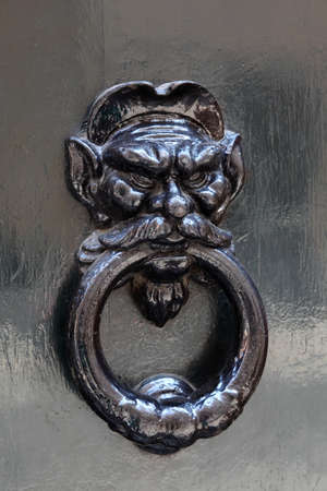 big beautiful metal doorknob, holding human head in his mouth stick