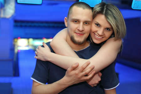 Girl hugs man and smiles during rest in bowling of club