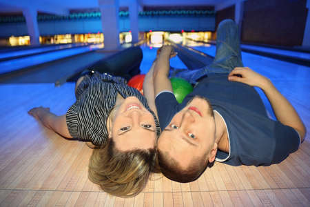 Youth and girl lie on back, holding on to hands and look upの写真素材