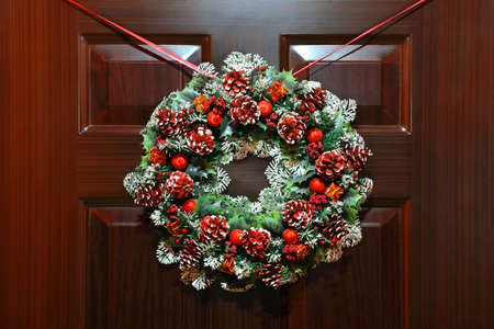 Large artificial circled wreath with knops and bead hangs during Christmas on doorの写真素材