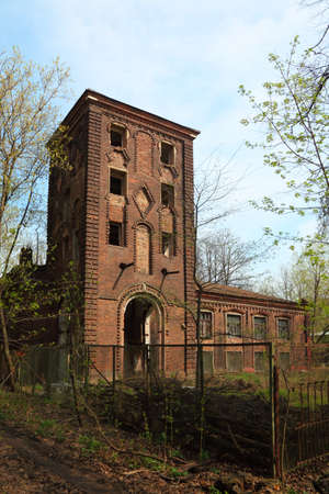 abandoned building with tower at spring, trees with first greenery