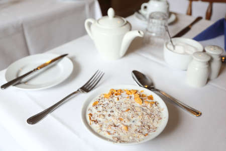 muesli in bowl of milk on table with white tablecloth, breakfastの写真素材