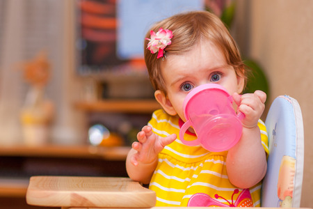 little girl sitting at the table. drink waterの写真素材