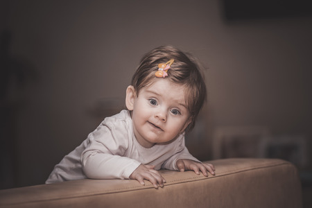 little girl stands near the sofa at homeの写真素材