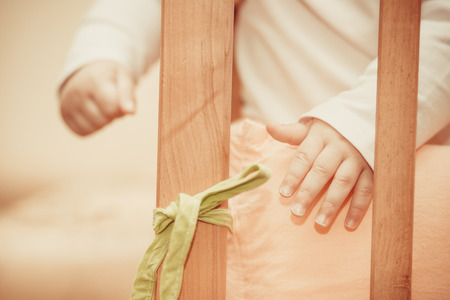 small child standing in a crib in clothesの写真素材