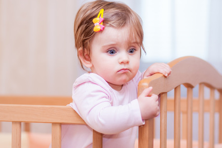 small child with a hairpin standing in cribの写真素材
