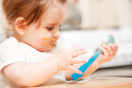 little girl feeding from a spoon on blue chairの写真素材
