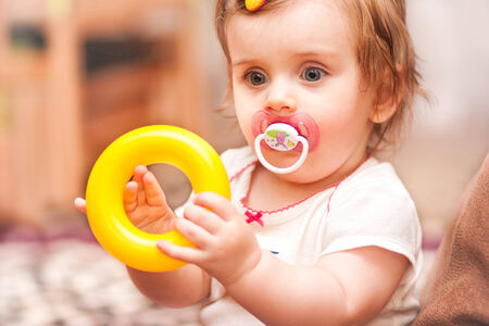 little girl sitting playing with a toy ringの写真素材