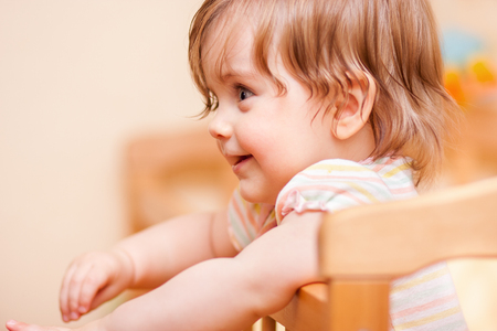 cheerful little girl standing in the crib at homeの写真素材
