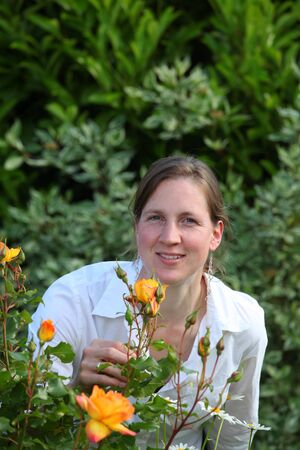 Attractive smiling young lady enjoys her gardenの写真素材