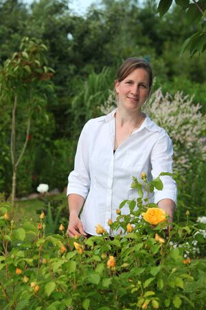 Attractive smiling young lady enjoys her gardenの写真素材