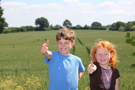 Happy young boy and girl with thumbs upの写真素材