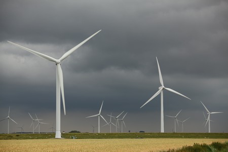 A windmill-powered plant in front of a dark and cloudy skyの写真素材