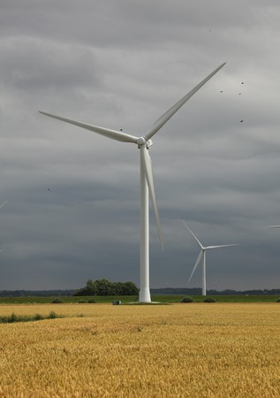 A windmill-powered plant in front of a dark and cloudy skyの写真素材