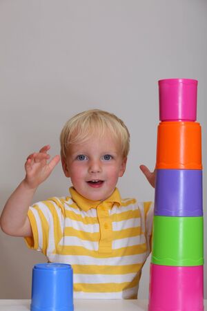 Young boy tries to build stacking towerの写真素材