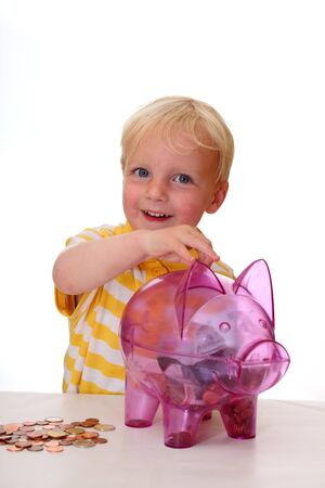 Happy kid fills his piggy bank with coinsの写真素材