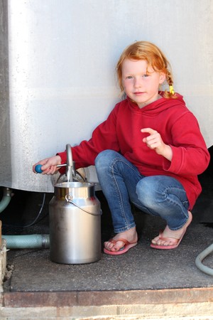 Girl fills milkcan from milk tankの写真素材
