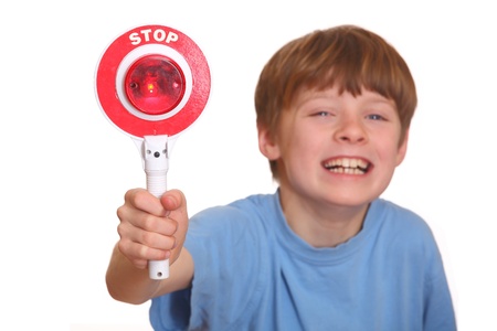 Laughing young boy shows stop sign isolated on white backgroundの写真素材