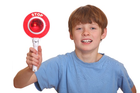 Poised young boy shows stop sign isolated on white backgroundの写真素材