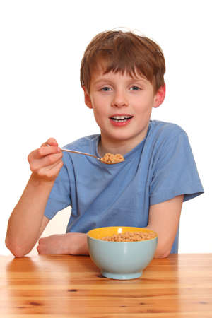 Portrait of a young boy eating cereals isolated on white backgroundの写真素材