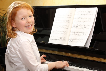Portrait of a happy young girl playing pianoの写真素材