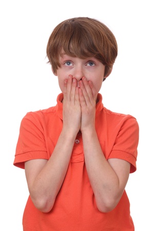 Portrait of a frightened boy covering his mouthの写真素材